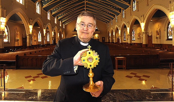 Father Michael Burzynski, pastor of St. John Gilbert in Cheektowaga, holds a relic from St. Francis of Assisi as he stand at the altar of the church, which was recently restored. He has donated his relic collection, of more than 1,100 pieces, which dates